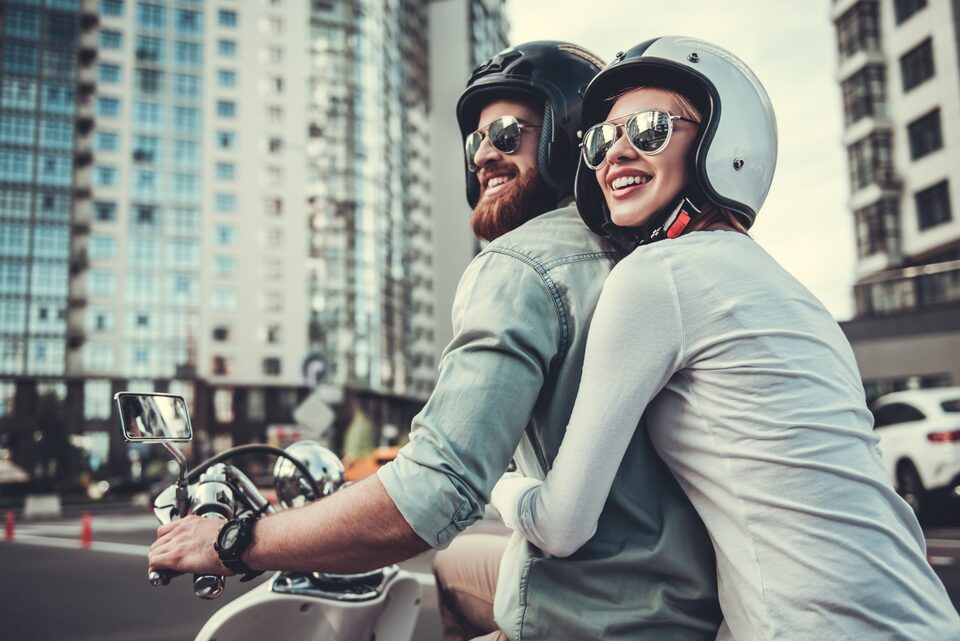 Un couple casqué circulant à scooter en ville