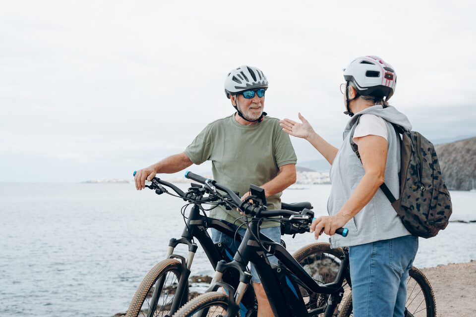 Deux cyclistes casqués faisant une pause avec leur vélo électrique en bord de mer